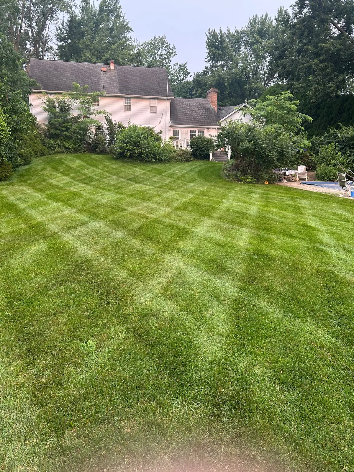 Crosshatched mowing lines across a green backyard