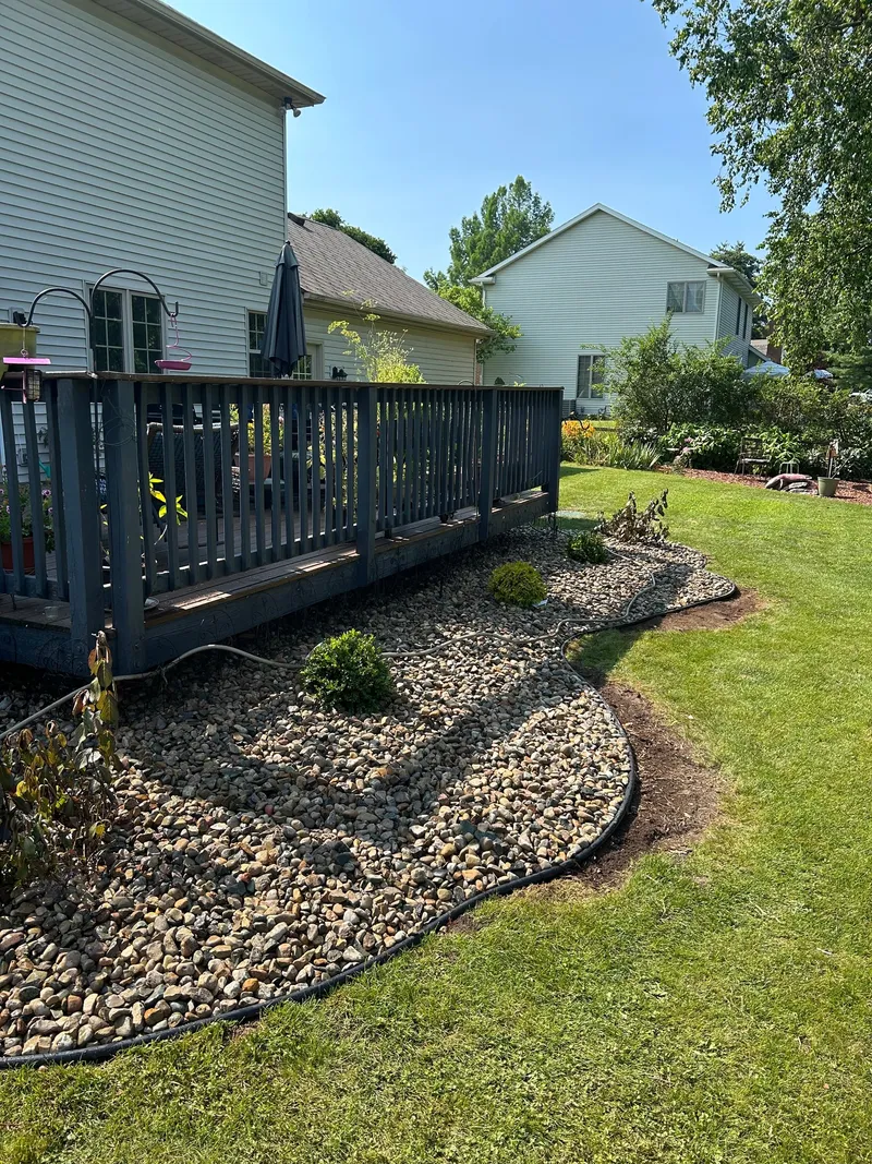 Curved stone beds and small shrubs alongside a raised deck