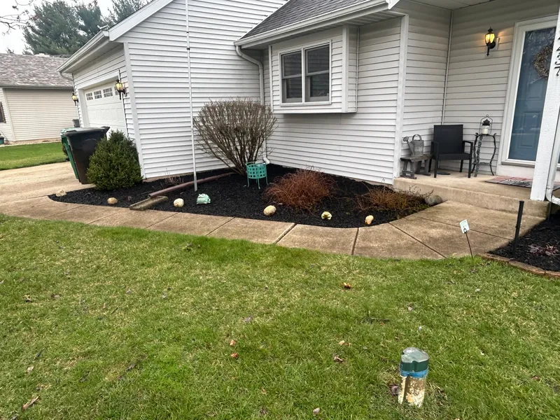Dark mulch and trimmed shrubs beside a light-sided home
