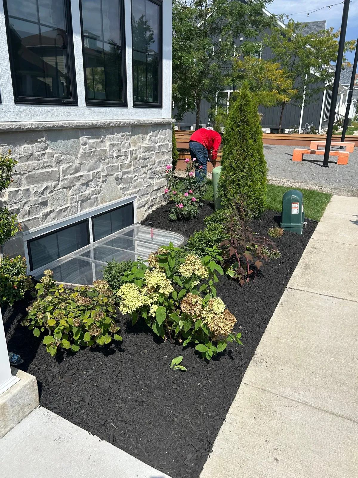 Fresh dark mulch and flowering plants beside a stone porch and front walkway