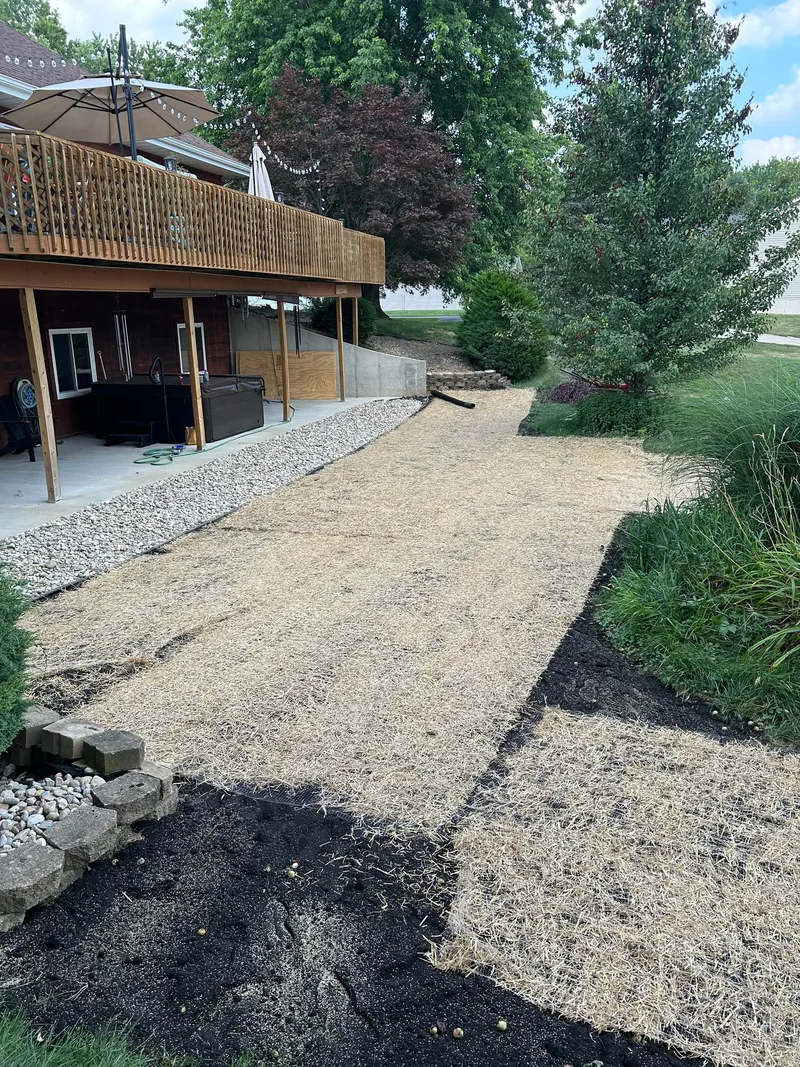 A stone border and straw-covered ground below a raised wooden deck