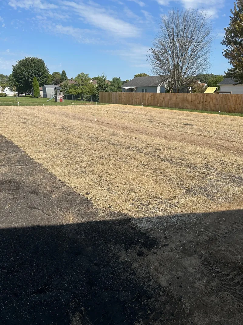 Straw-covered ground across a yard during landscape work