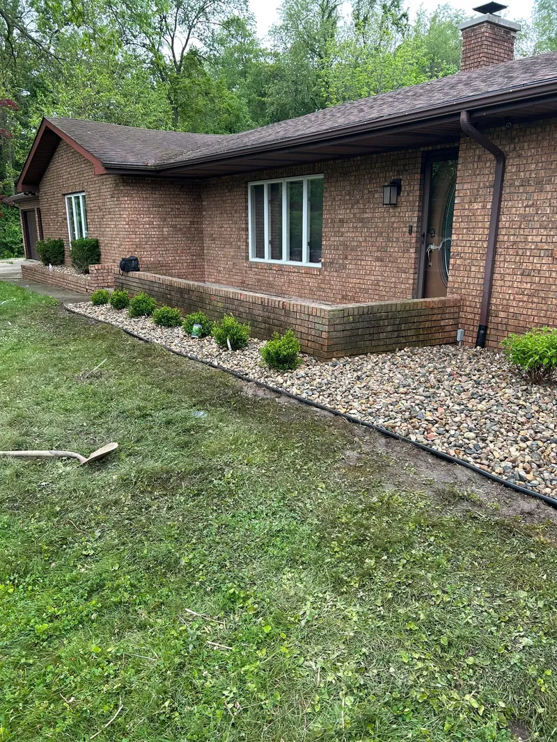 Light stone beds and small shrubs along a brick home's entrance