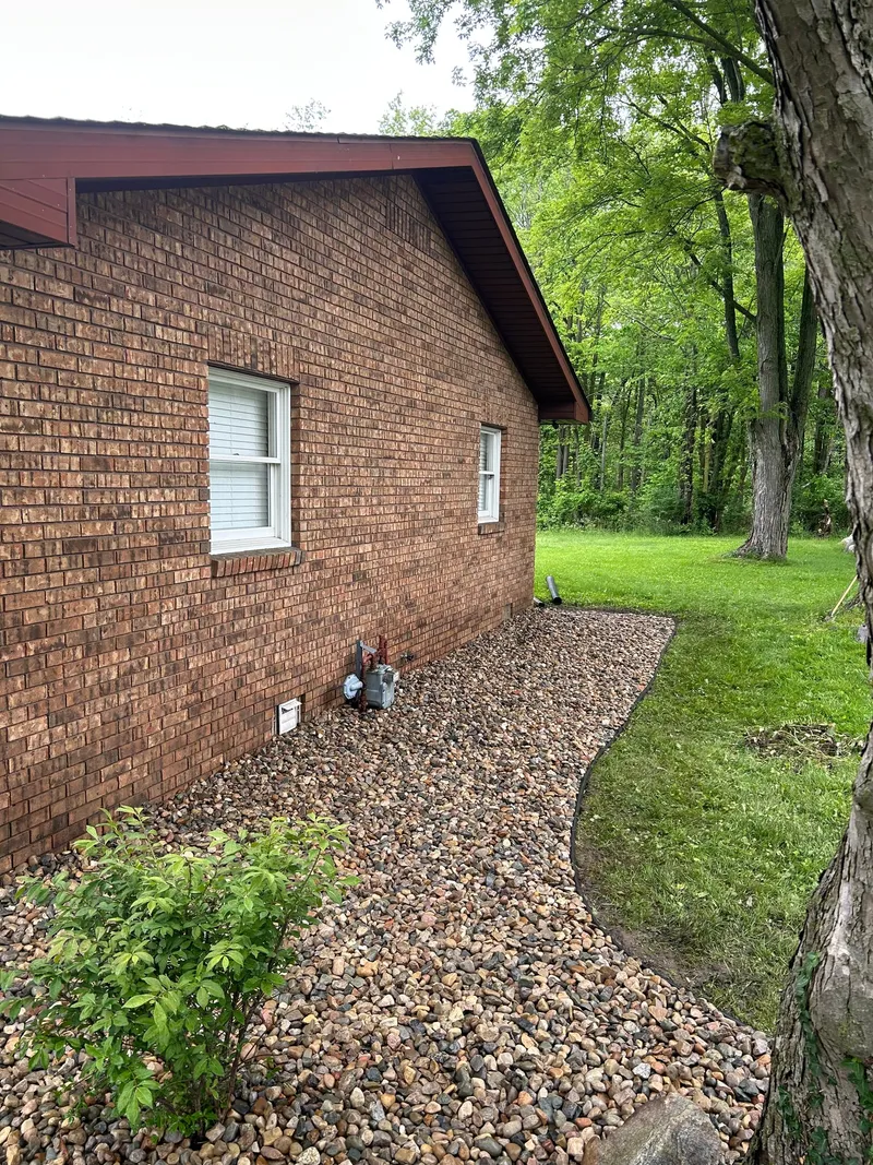A light stone bed beneath a side window of a brick home