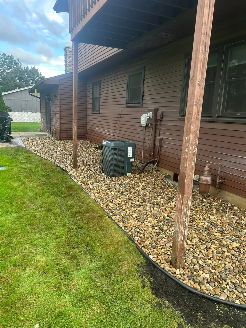Fresh stone beds along brown house siding and timber posts