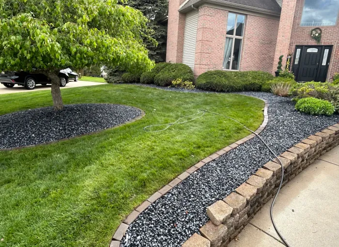 Curved planting beds with shrubs and decorative stone