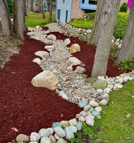 Red mulch and decorative white rock around trees