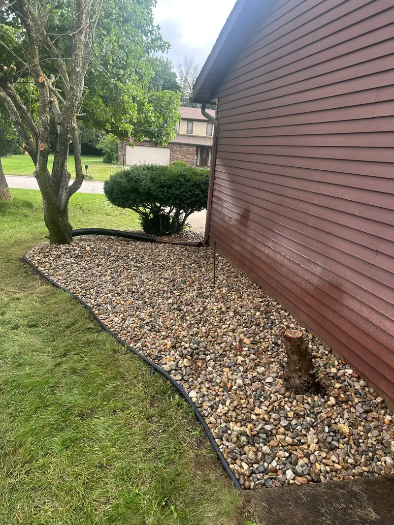 A tidy stone border around a side yard beside brown siding