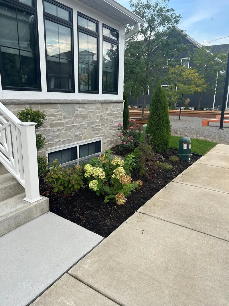 Flowering plants beside a stone porch before the mulch refresh